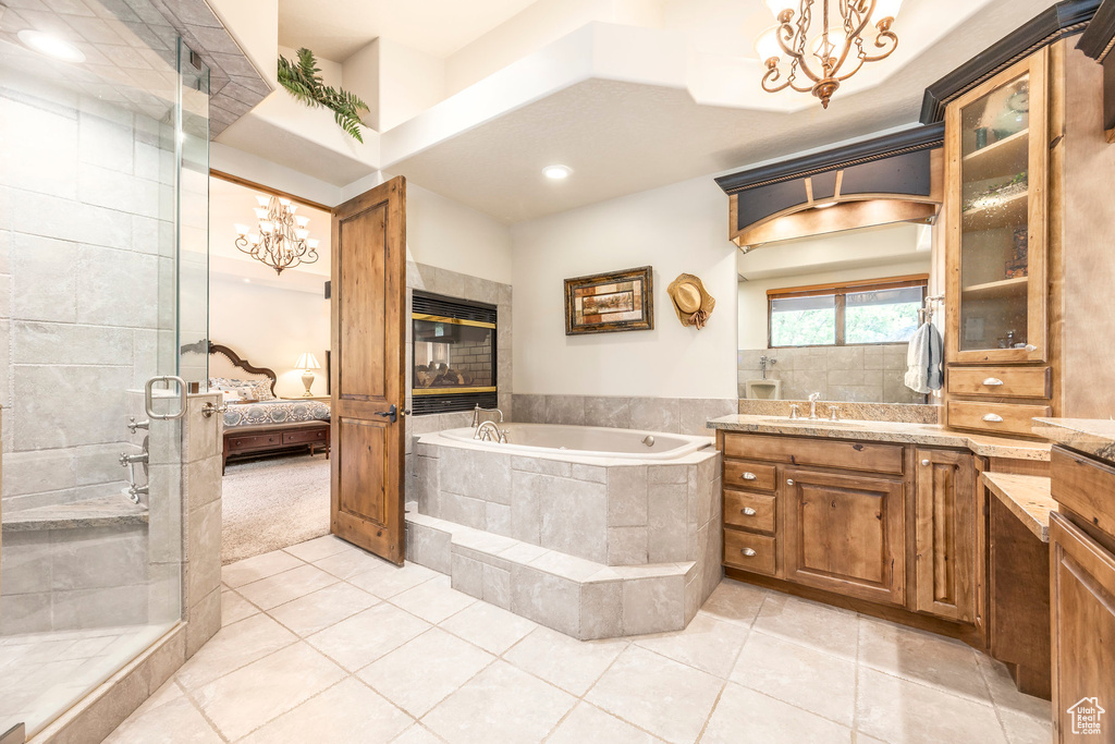 Ensuite bathroom with a chandelier, a garden tub, a shower stall, tile patterned floors, and vanity