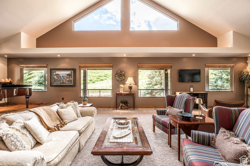 Living room with healthy amount of natural light, high vaulted ceiling, and carpet