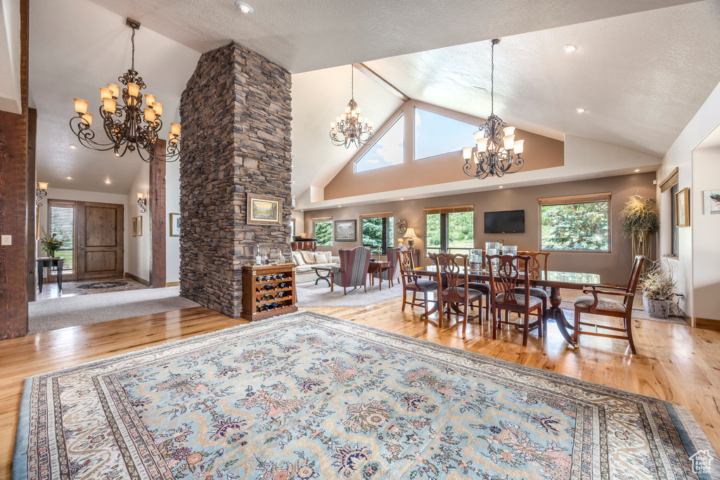 Dining space featuring a chandelier, wood finished floors, plenty of natural light, high vaulted ceiling, and recessed lighting