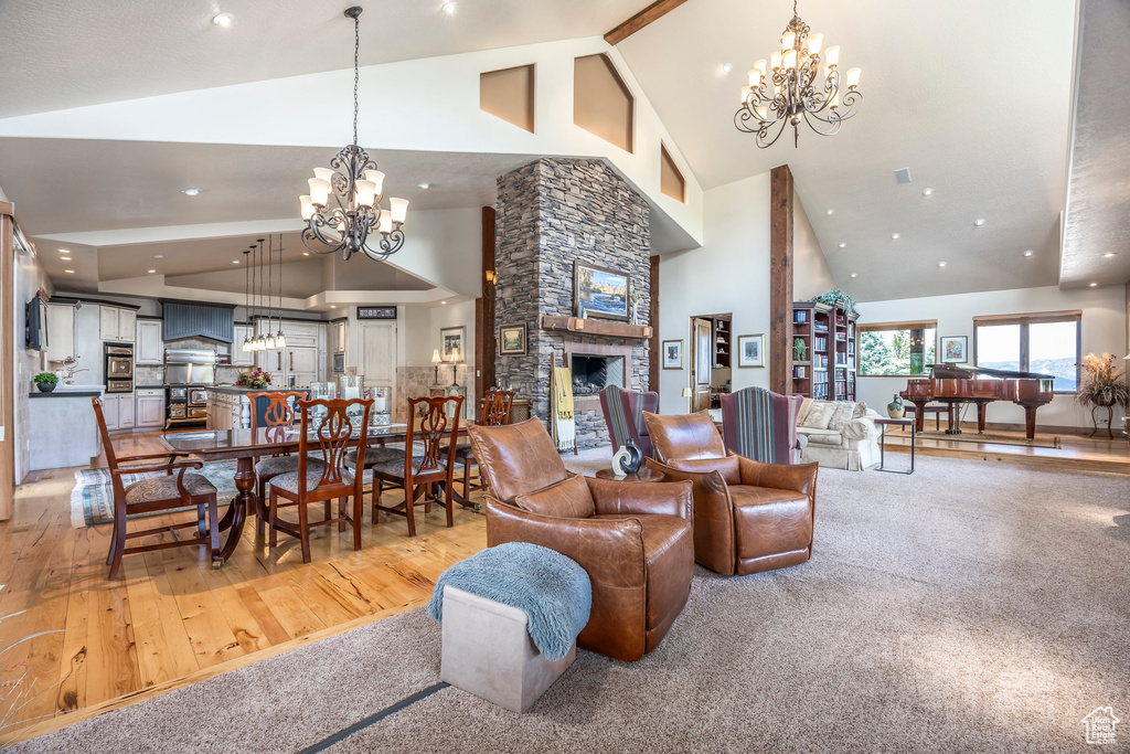 Living room with high vaulted ceiling, a chandelier, light wood-style floors, a fireplace, and recessed lighting