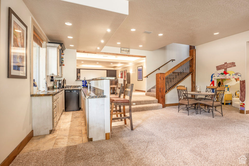 Kitchen featuring dishwashing machine, a peninsula, recessed lighting, light carpet, and a textured ceiling