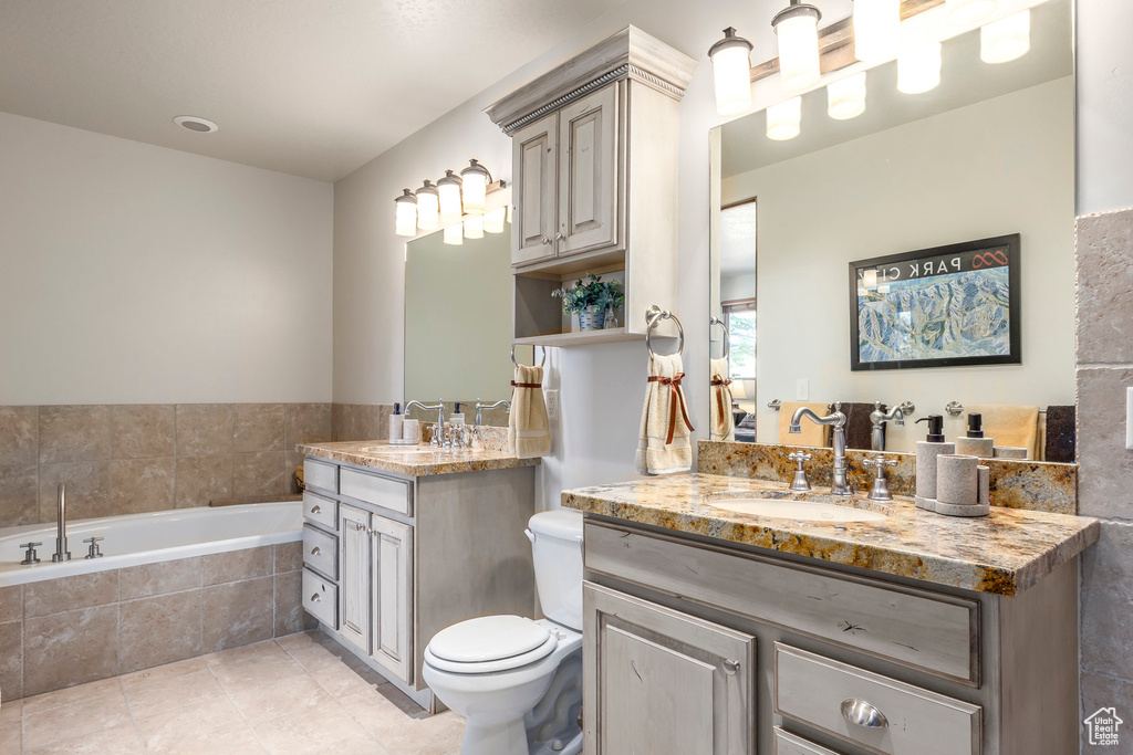 Full bath with two vanities, a garden tub, and tile patterned floors