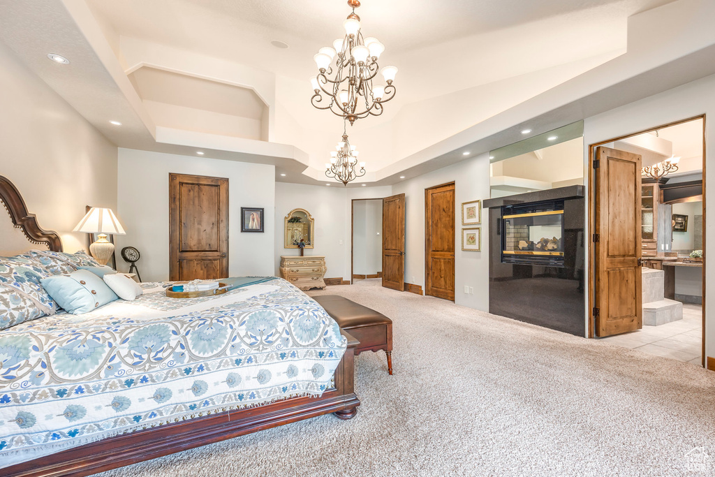 Bedroom featuring light colored carpet, recessed lighting, a chandelier, a multi sided fireplace, and ensuite bathroom