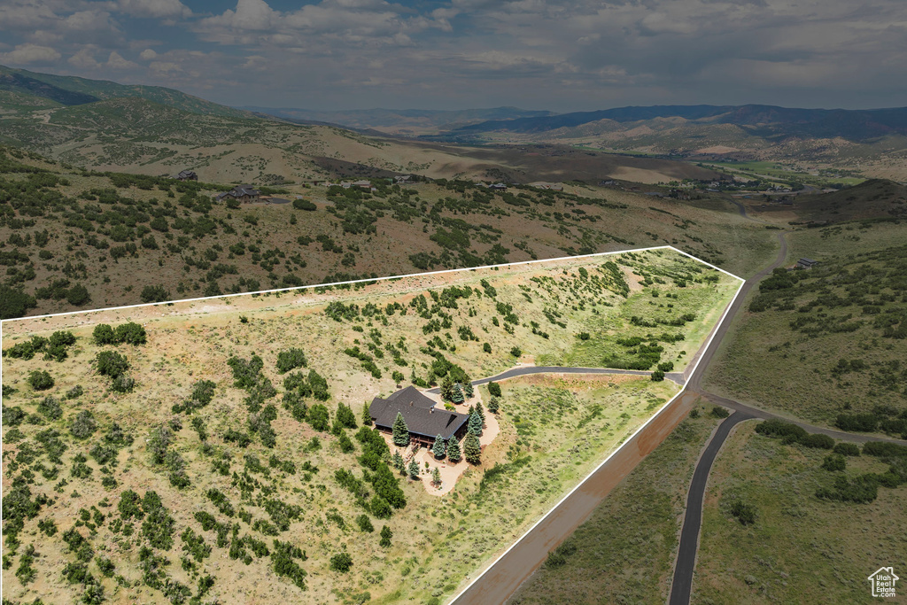 Aerial view of property and surrounding area featuring property boundaries highlighted, a mountainous background, and rural landscape