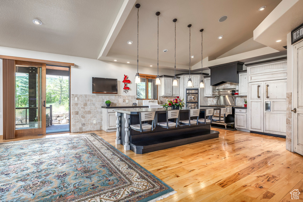 Living area with light wood-type flooring, vaulted ceiling, and recessed lighting