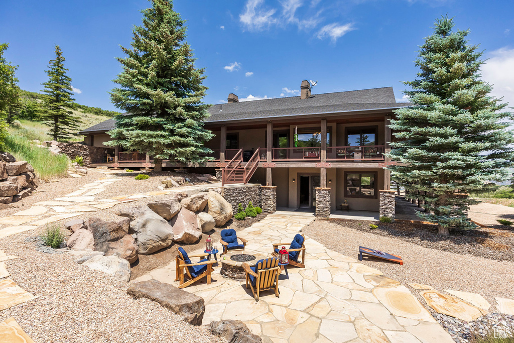 Rear view of property with an outdoor fire pit, a patio area, stairs, stucco siding, and roof with shingles