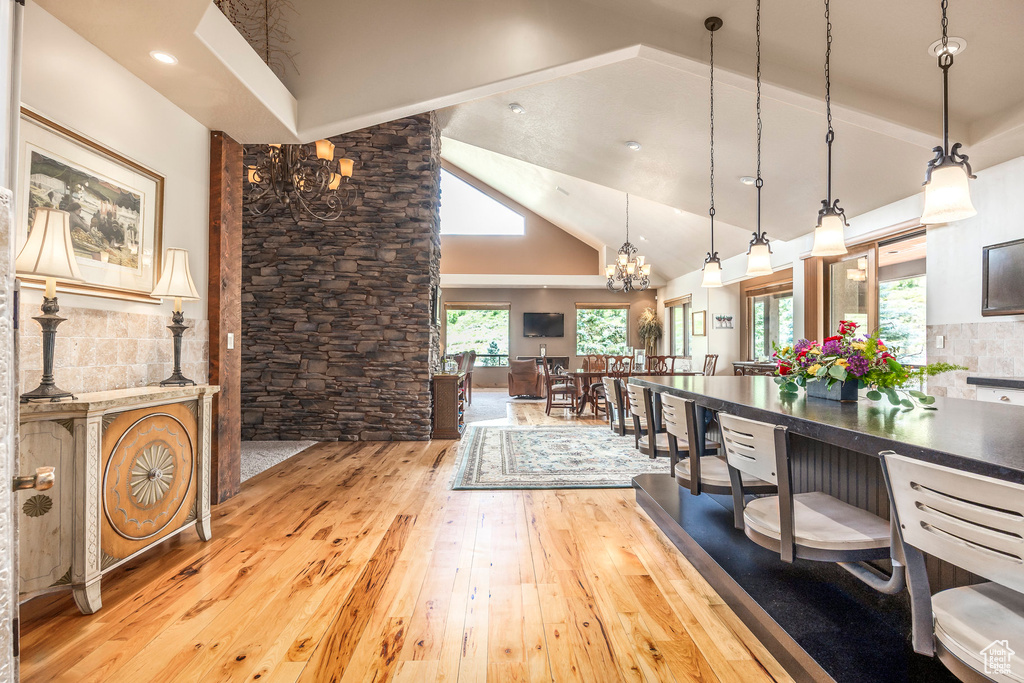 Kitchen with light wood-type flooring, a chandelier, decorative light fixtures, and high vaulted ceiling