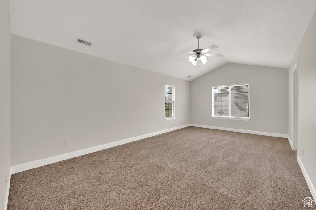 Empty room featuring a ceiling fan, carpet floors, and lofted ceiling