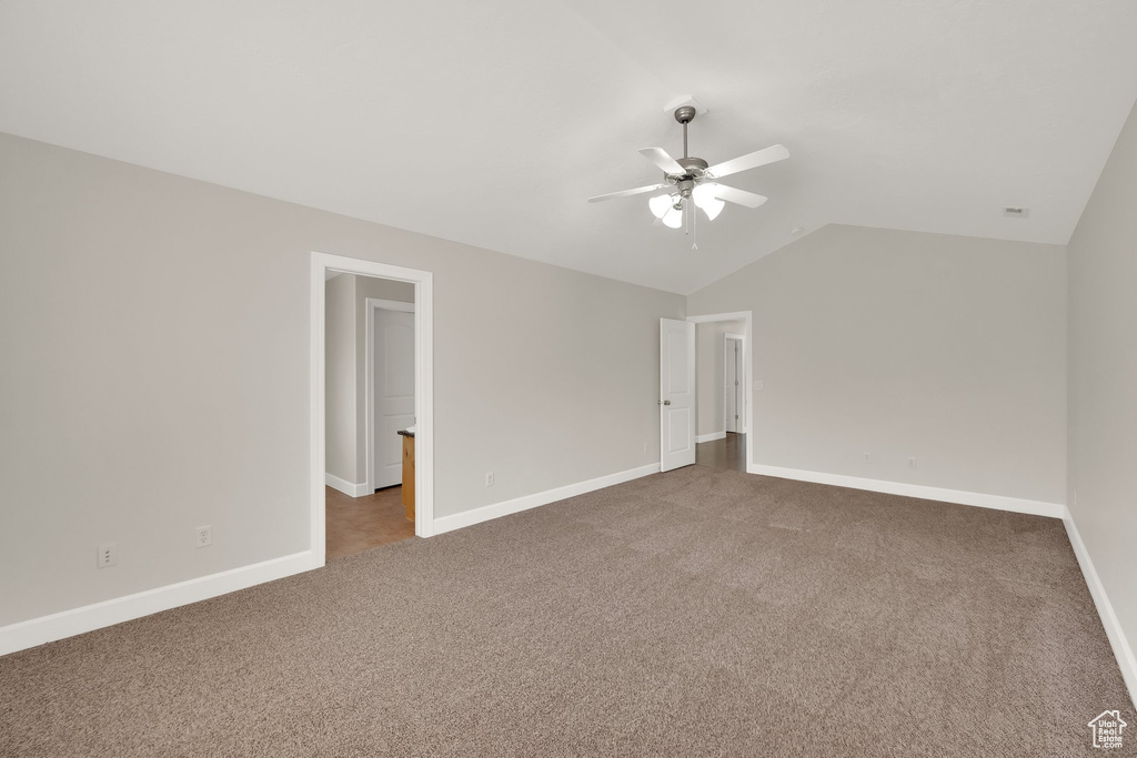 Carpeted spare room with ceiling fan and lofted ceiling