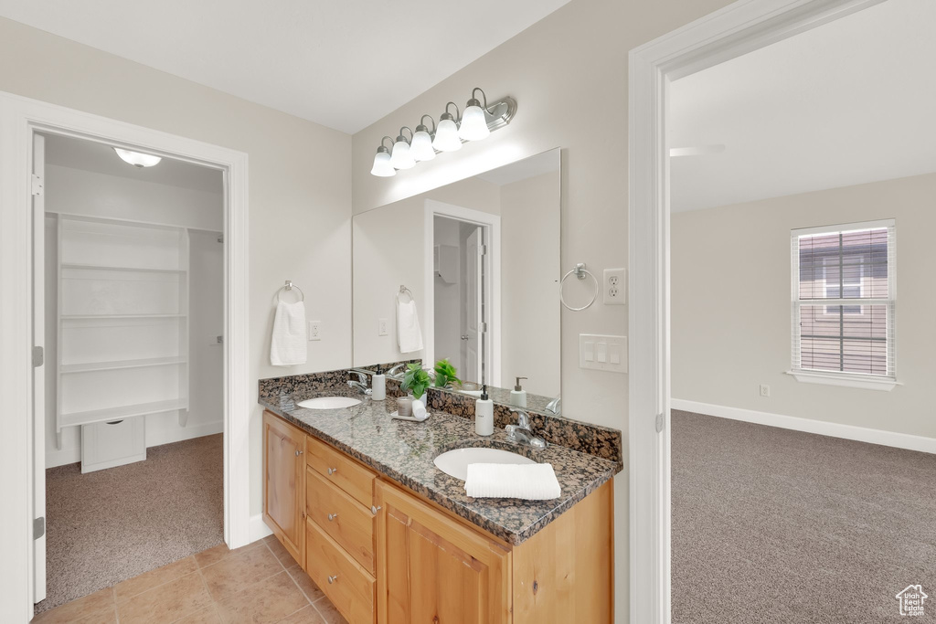 Full bath with double vanity, tile patterned floors, and a walk in closet