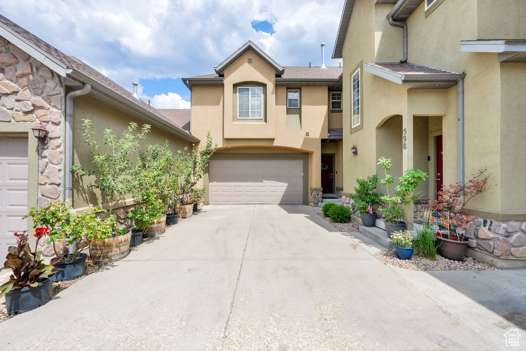 View of property featuring stucco siding, driveway, and an attached garage