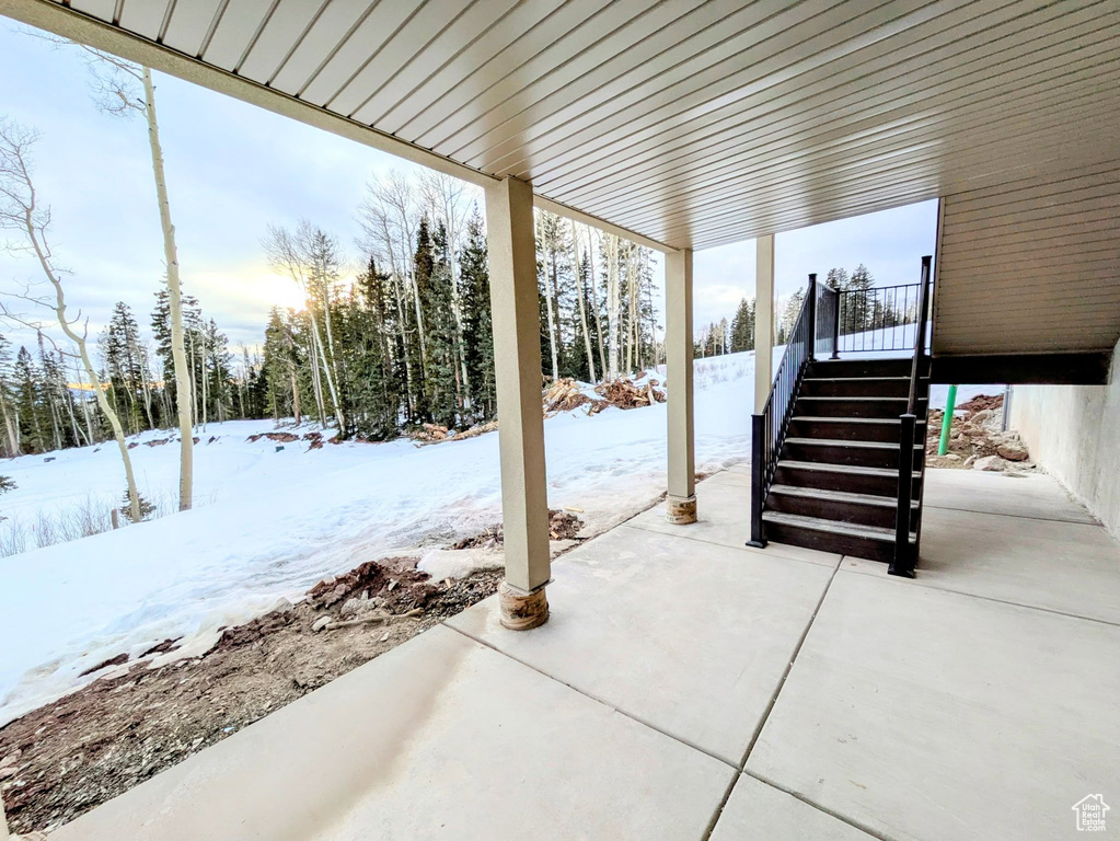 Snow covered patio featuring a patio and stairs