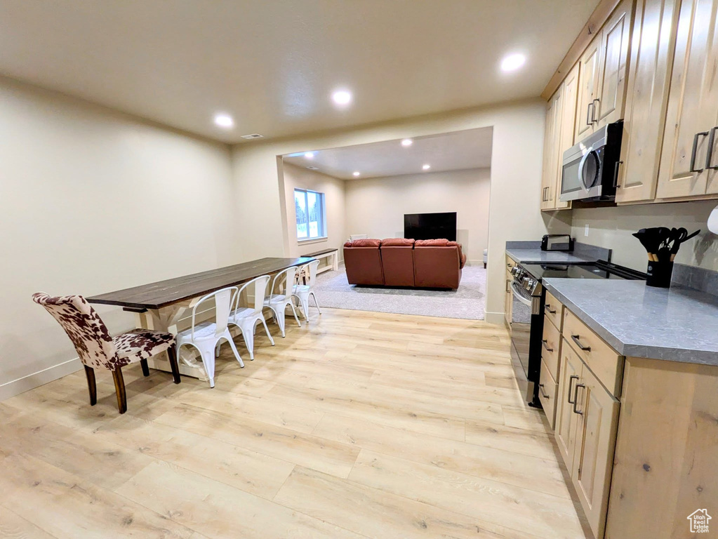 Kitchen featuring appliances with stainless steel finishes, light wood-style flooring, recessed lighting, and dark countertops