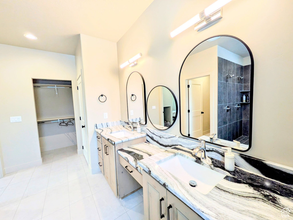 Full bath featuring vanity, tile patterned floors, tiled shower, and a walk in closet