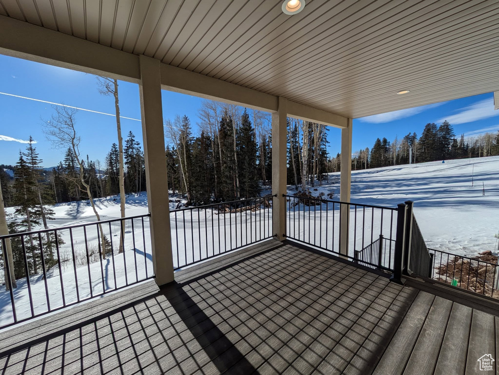 Snow covered deck featuring view of scattered trees