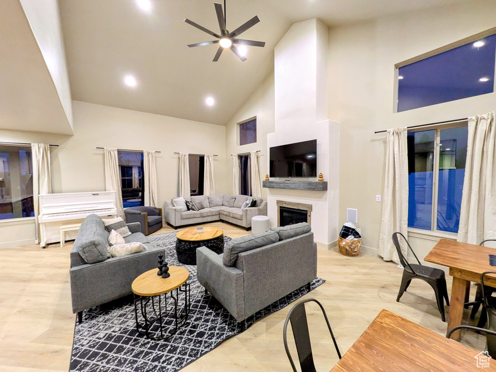 Living room with high vaulted ceiling, a ceiling fan, a glass covered fireplace, and recessed lighting