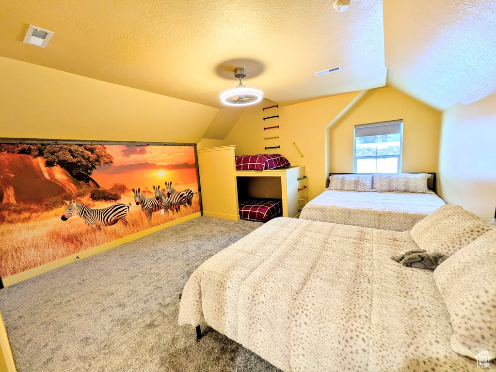 Bedroom featuring vaulted ceiling, carpet, and a textured ceiling