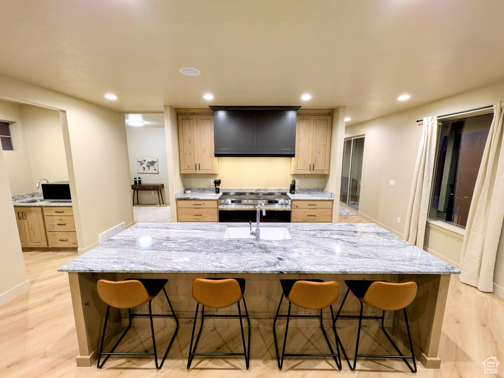 Kitchen featuring electric stove, a breakfast bar, light wood-type flooring, a spacious island, and recessed lighting