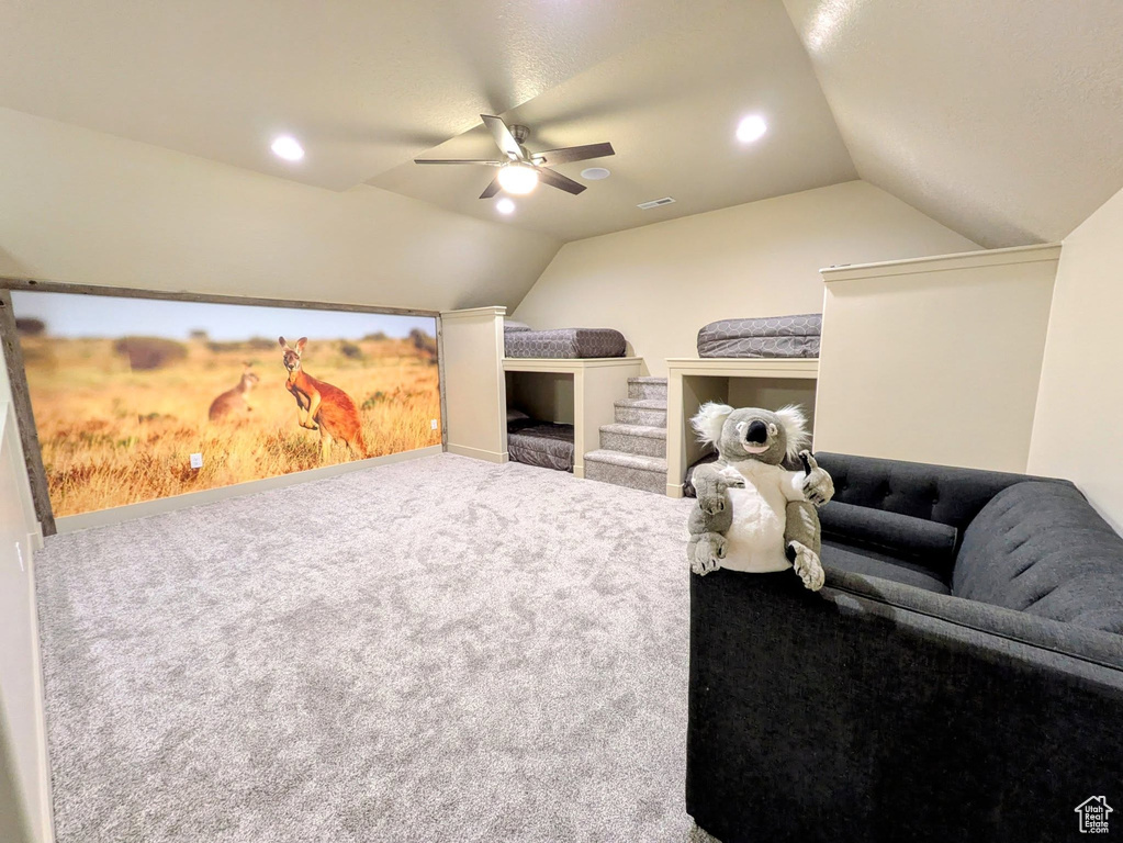 Carpeted cinema room with vaulted ceiling, a ceiling fan, and recessed lighting