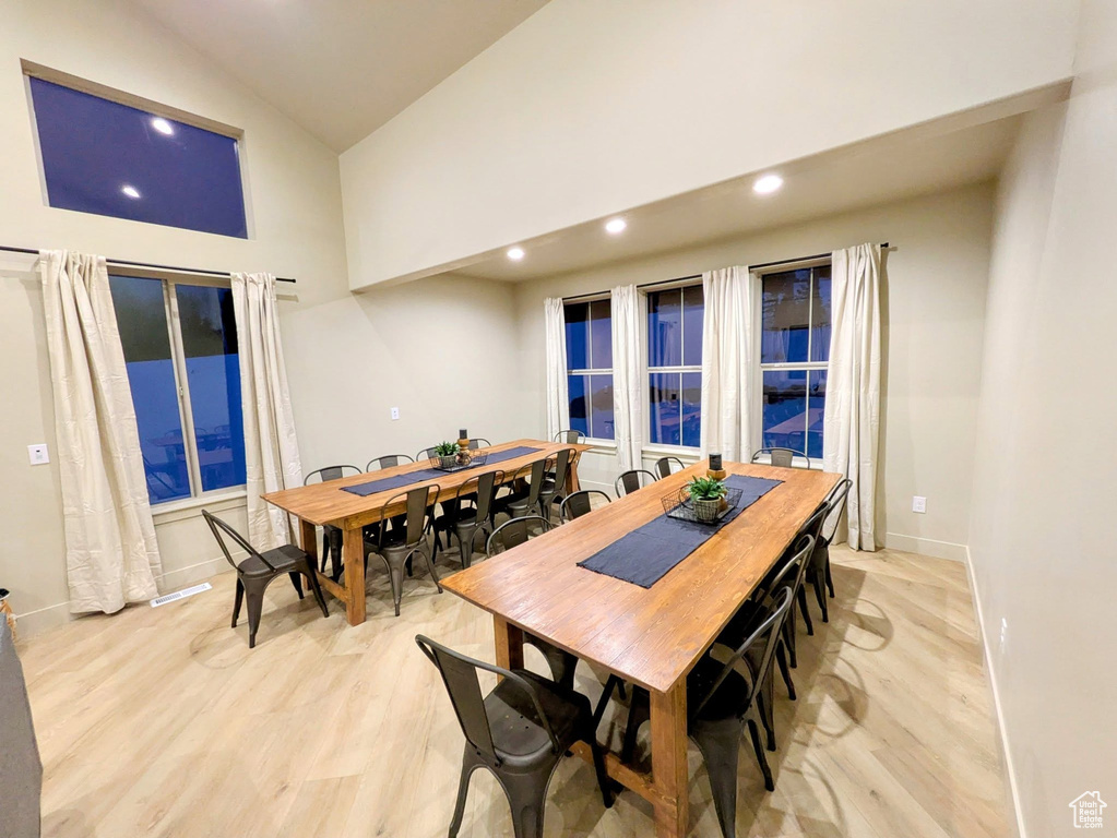 Dining room with high vaulted ceiling, recessed lighting, and light wood-type flooring