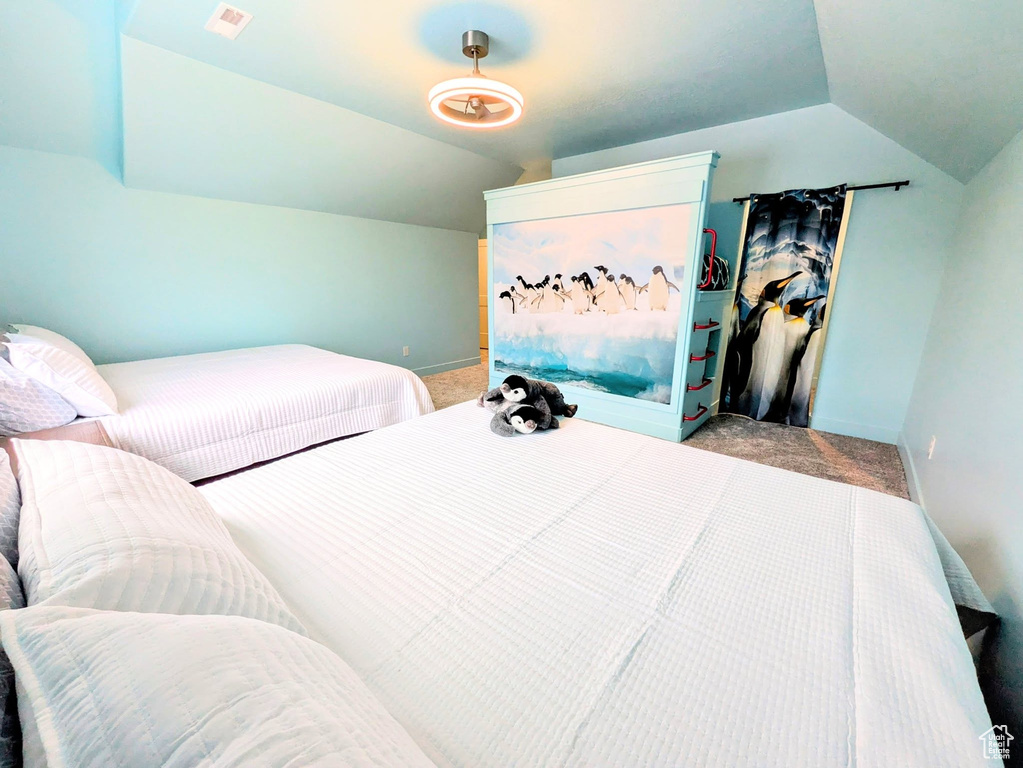 Carpeted bedroom with vaulted ceiling and baseboards