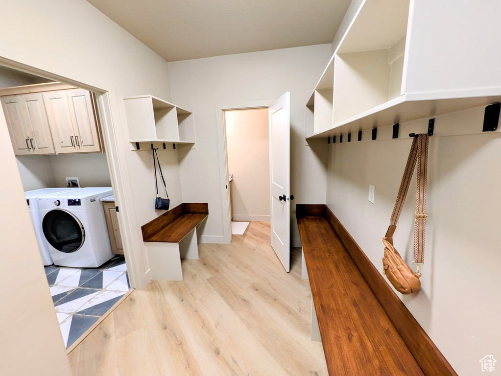 Washroom featuring cabinet space, washer / dryer, and light wood-style flooring