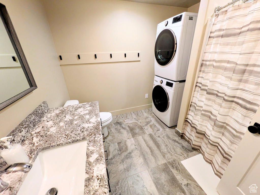 Washroom with stacked washer and clothes dryer and baseboards