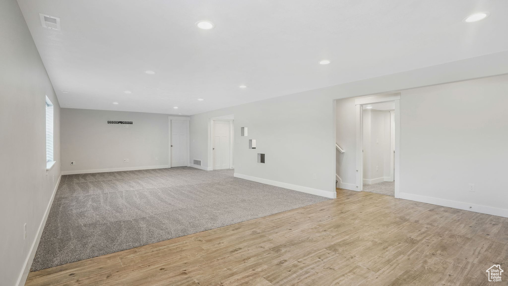 Spare room featuring stairs, recessed lighting, light wood-type flooring, and light colored carpet