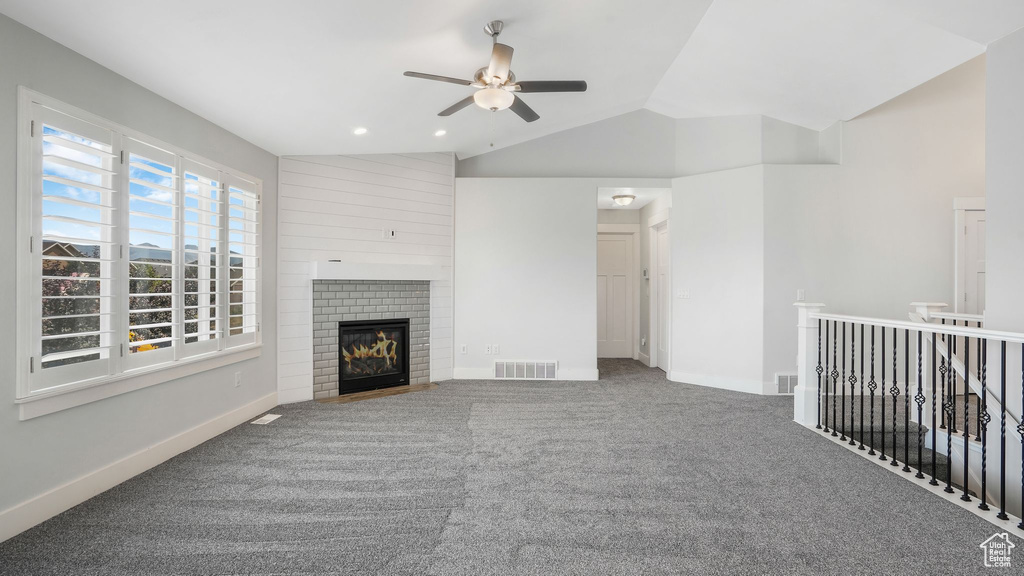 Unfurnished living room featuring ceiling fan, vaulted ceiling, carpet floors, a fireplace, and recessed lighting