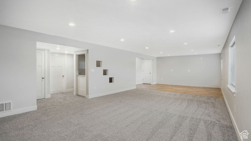Empty room with light carpet and recessed lighting