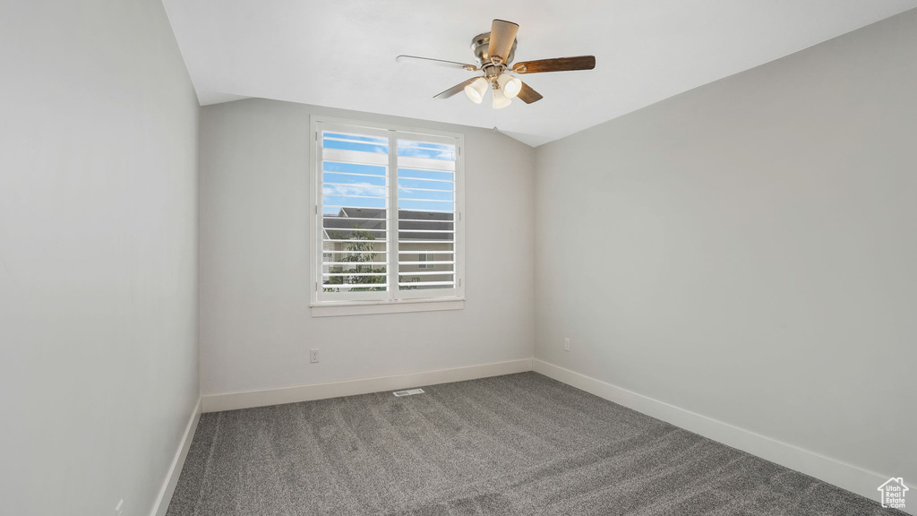 Carpeted spare room with a ceiling fan and baseboards