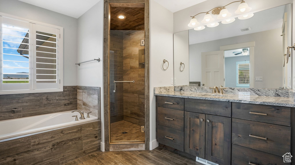 Bathroom with wood finished floors, vanity, a garden tub, a stall shower, and ceiling fan