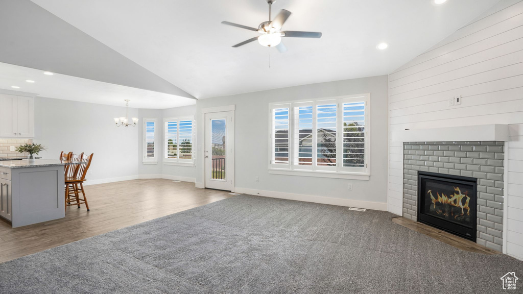 Living room featuring a chandelier, a fireplace, ceiling fan, wood finished floors, and recessed lighting