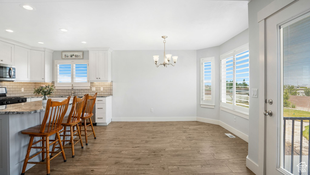 Kitchen with gas stove, stainless steel microwave, wood finished floors, decorative backsplash, and recessed lighting