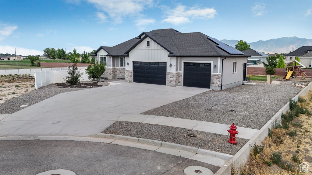 View of front of property with a garage, board and batten siding, driveway, roof with shingles, and a mountain view