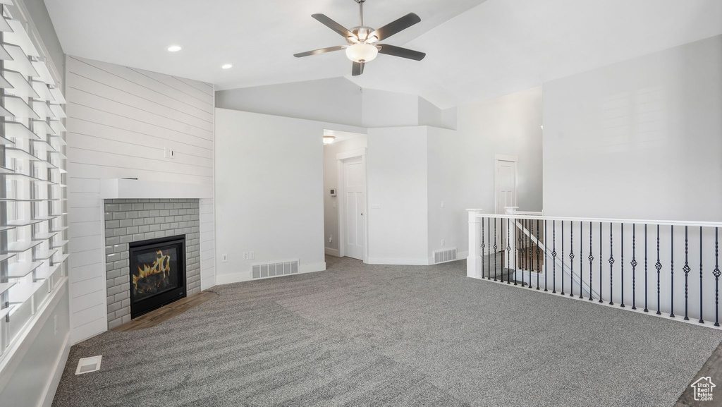 Unfurnished living room with vaulted ceiling, ceiling fan, carpet, a glass covered fireplace, and recessed lighting