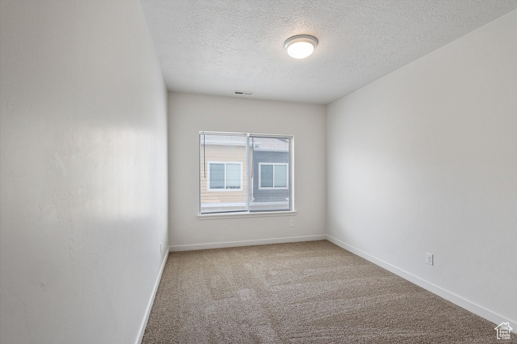 Unfurnished room featuring a textured ceiling and carpet flooring