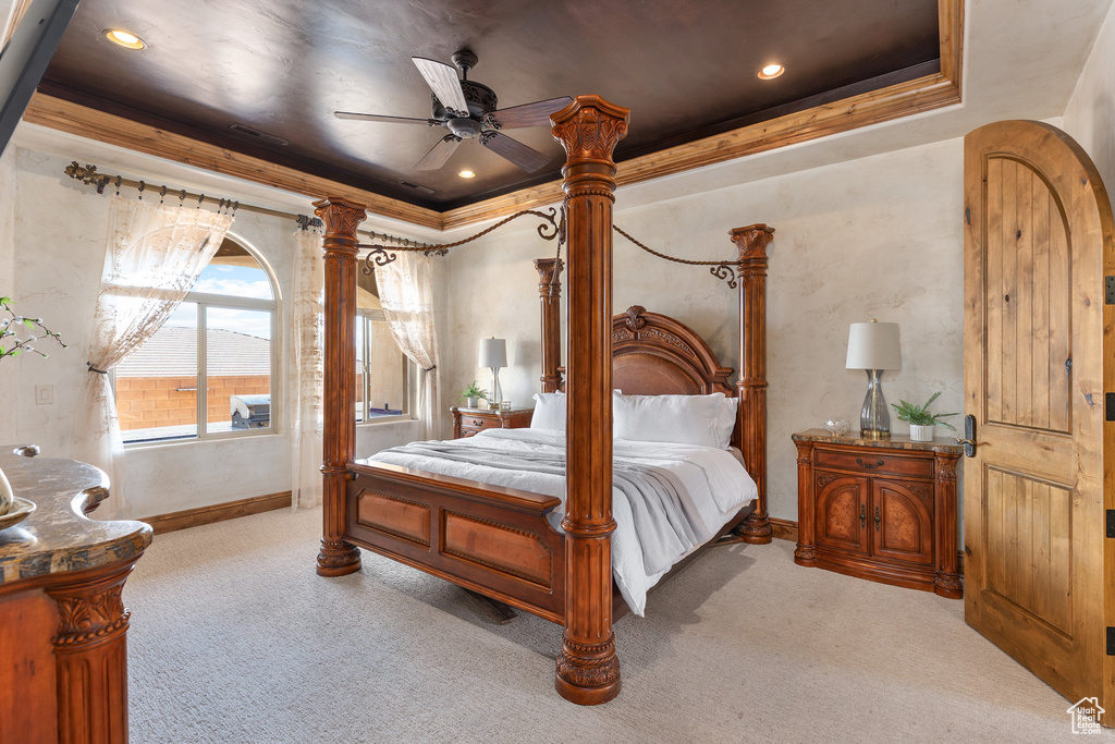Carpeted bedroom with a tray ceiling, crown molding, a ceiling fan, and recessed lighting