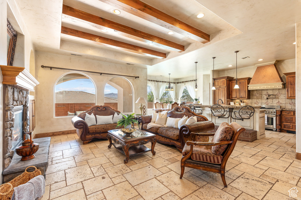 Living area with stone tile floors, beamed ceiling, recessed lighting, and a stone fireplace