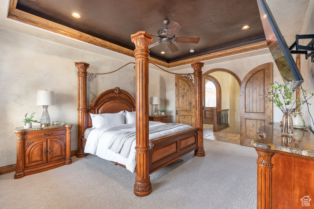 Carpeted bedroom with recessed lighting, a tray ceiling, arched walkways, and crown molding