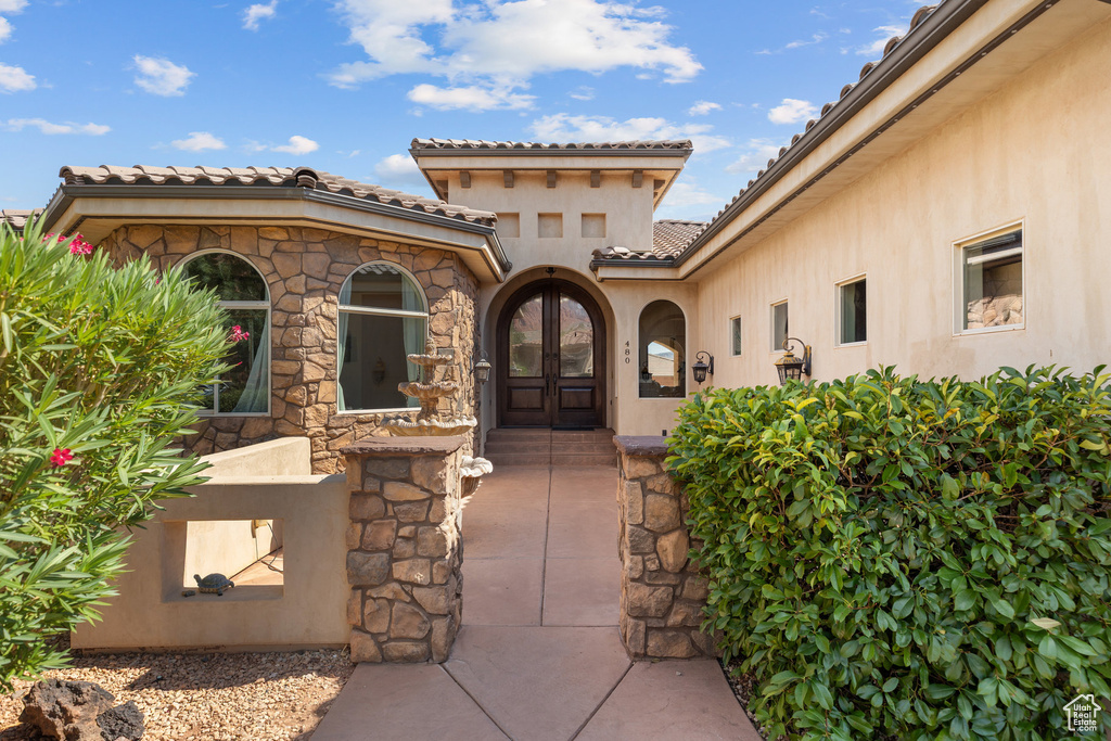 View of exterior entry featuring a tile roof, stucco siding, and french doors