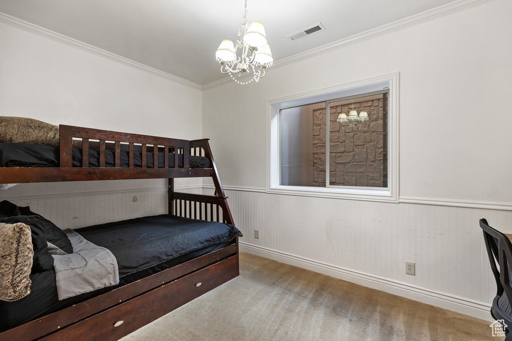 Bedroom featuring a chandelier, carpet flooring, ornamental molding, and wainscoting