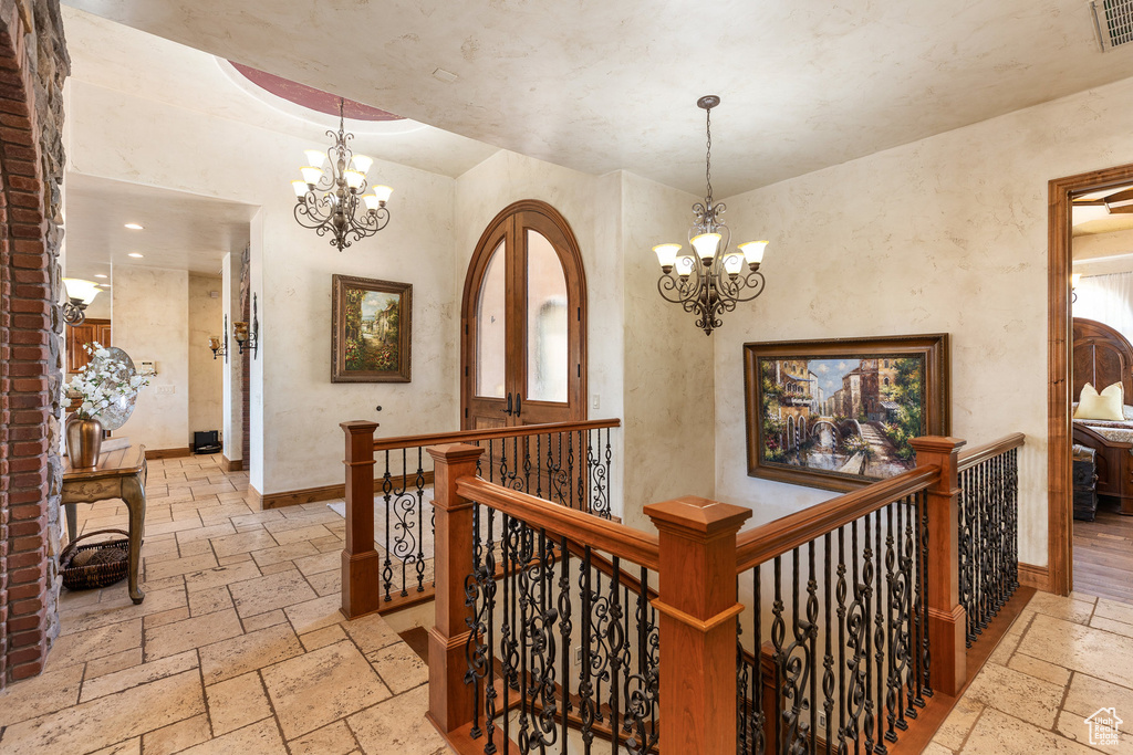 Hall featuring stone tile floors, a chandelier, an upstairs landing, and recessed lighting