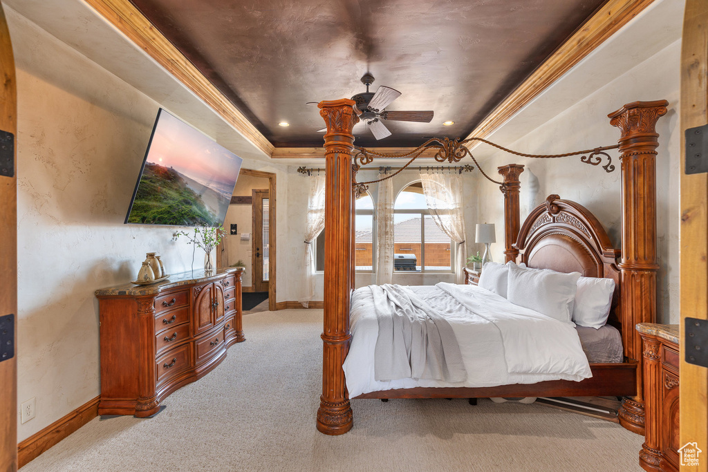Bedroom featuring light colored carpet, a tray ceiling, and crown molding
