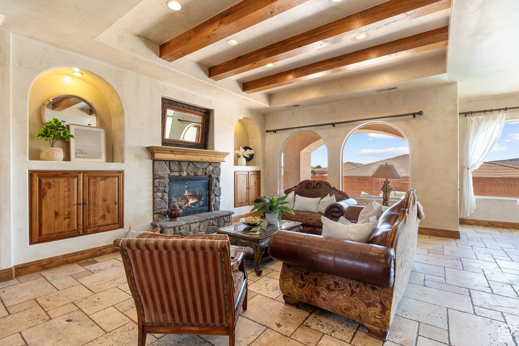 Living area with stone tile floors, beamed ceiling, a stone fireplace, and recessed lighting