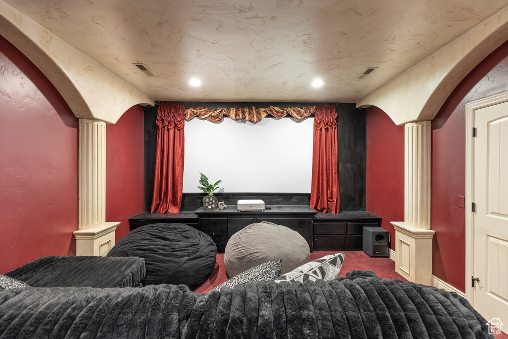Home theater room featuring ornate columns, carpet, arched walkways, and recessed lighting