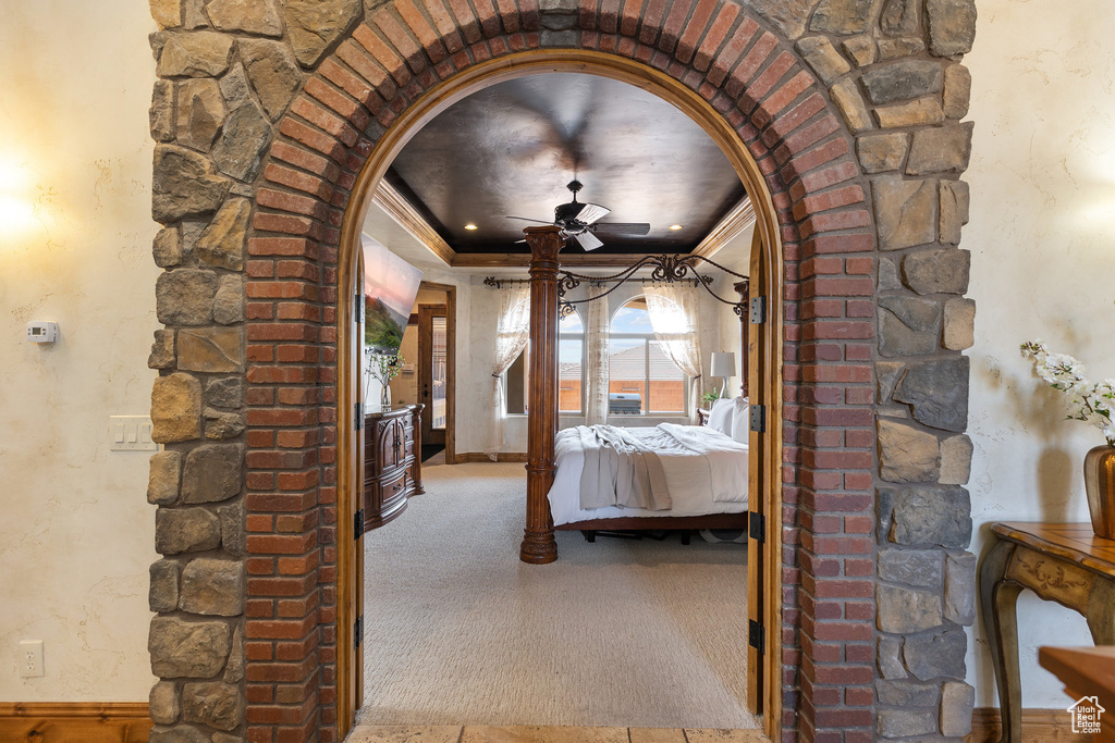 Unfurnished bedroom with arched walkways, carpet, crown molding, and a tray ceiling