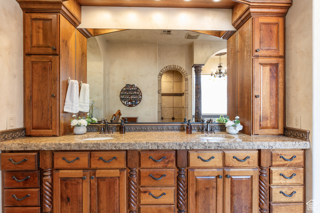 Bathroom featuring a chandelier and double vanity