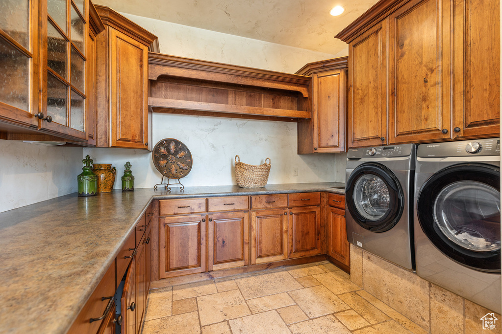 Laundry area with cabinet space, washer and clothes dryer, stone tile floors, and recessed lighting