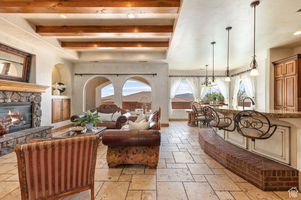 Living area with stone tile flooring, a fireplace, beam ceiling, and recessed lighting